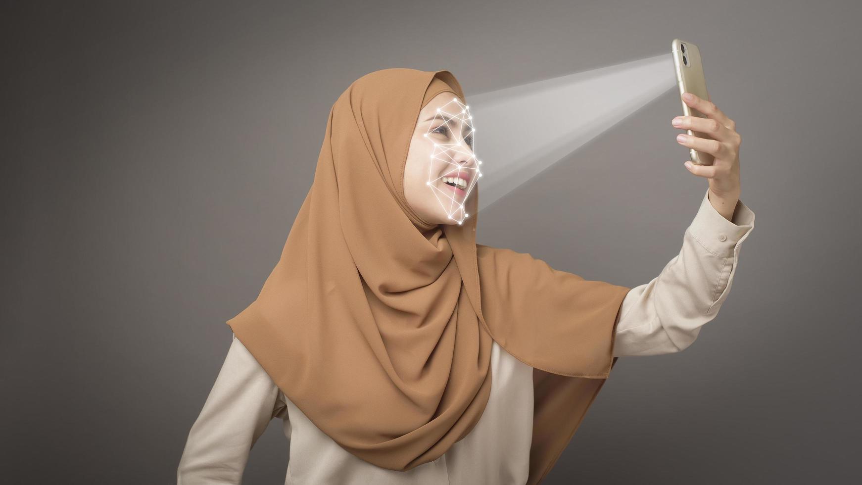 linda mulher está digitalizando seu rosto com o telefone inteligente do sistema de reconhecimento facial foto