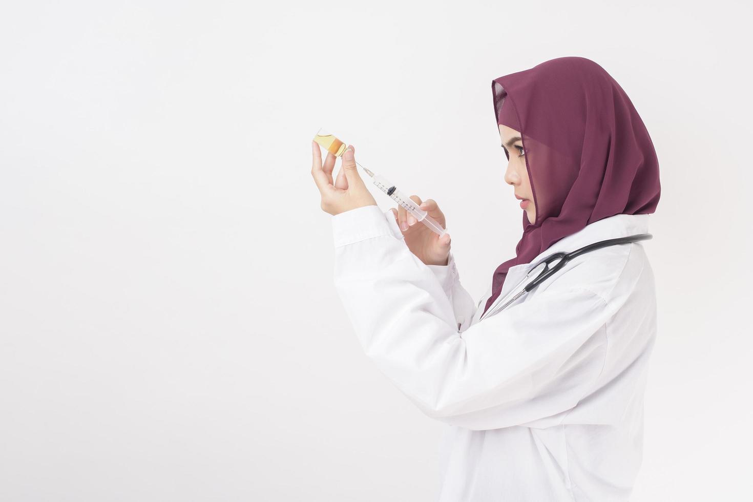 médico de mulher bonita com hijab está segurando vacina em fundo branco foto