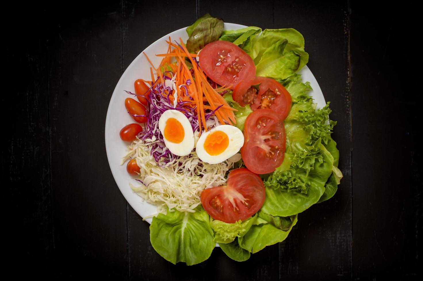 salada de legumes em fundo preto de madeira foto