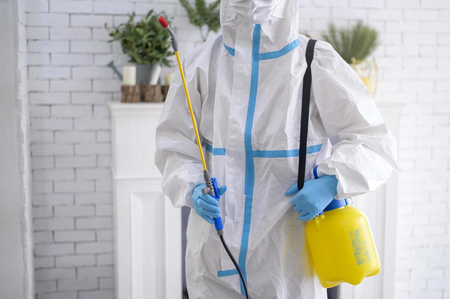 uma equipe médica em traje de EPI está usando spray desinfetante na sala de estar, proteção covid-19, conceito de desinfecção. foto