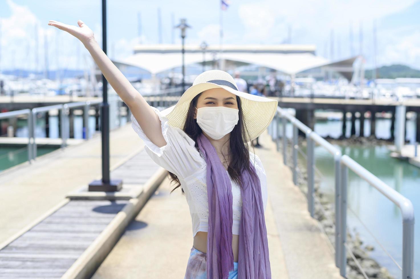 uma mulher viajante está usando máscara protetora no cais, viaja sob pandemia covid-19, viagens de segurança, protocolo de distanciamento social, novo conceito de viagem normal foto