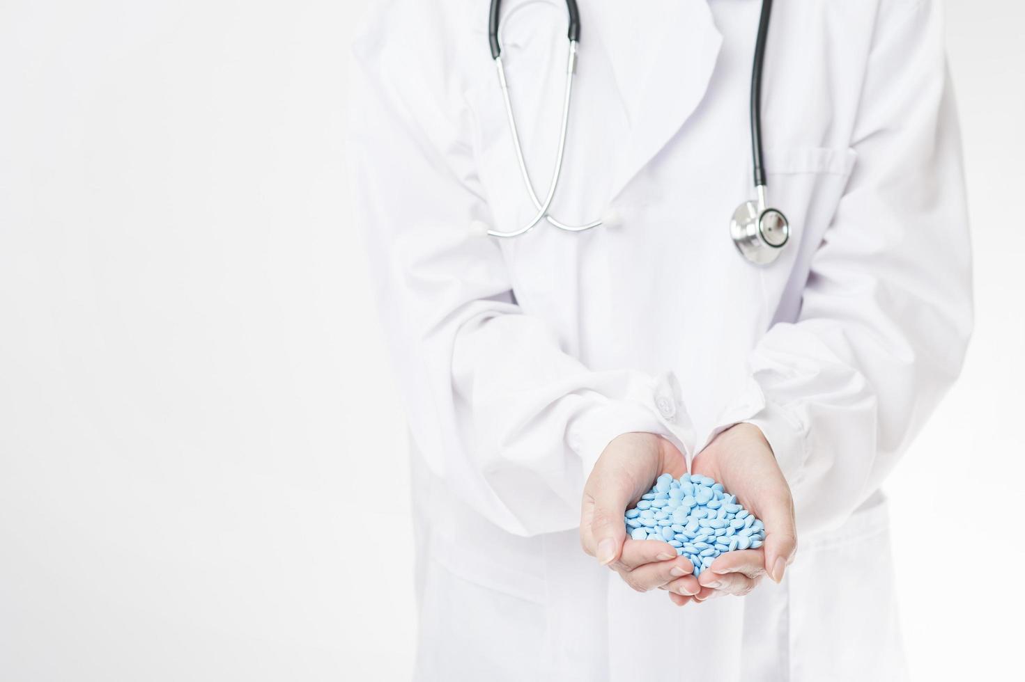 fechar a mão do médico está segurando pílulas no fundo branco foto
