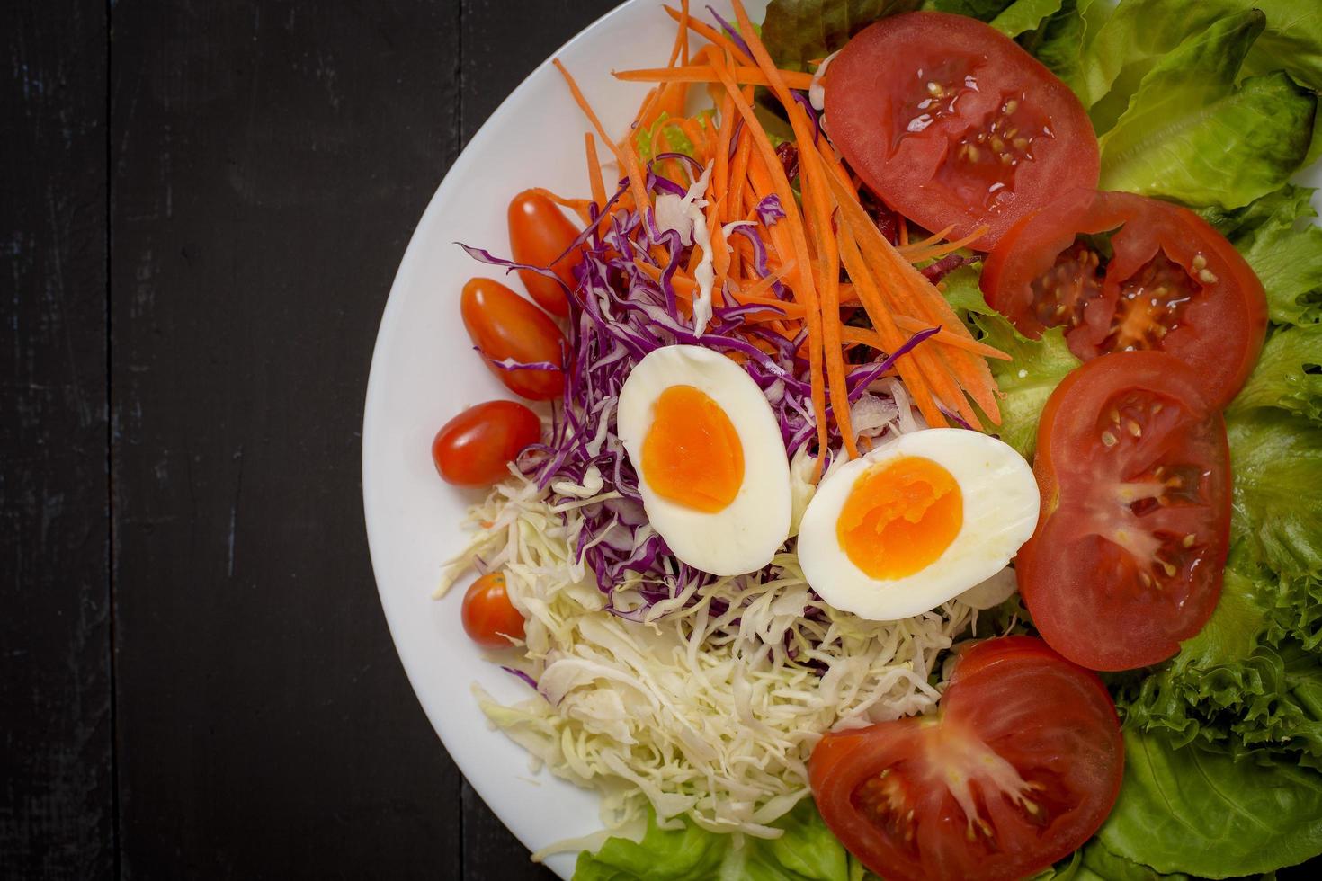 salada de legumes em fundo preto de madeira foto