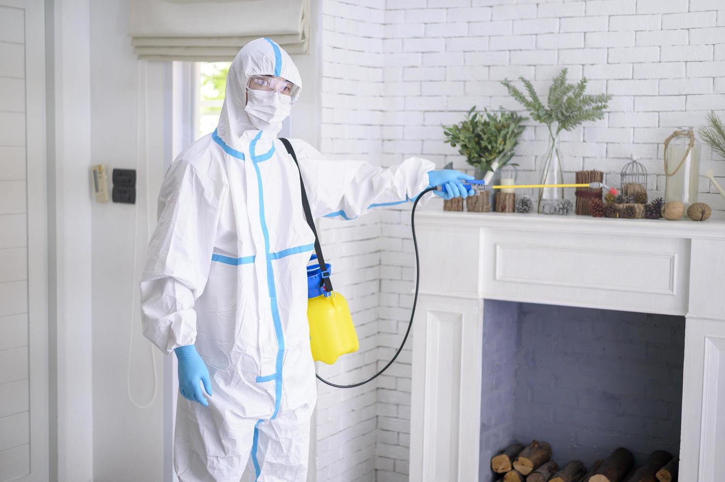 uma equipe médica em traje de EPI está usando spray desinfetante na sala de estar, proteção covid-19, conceito de desinfecção. foto
