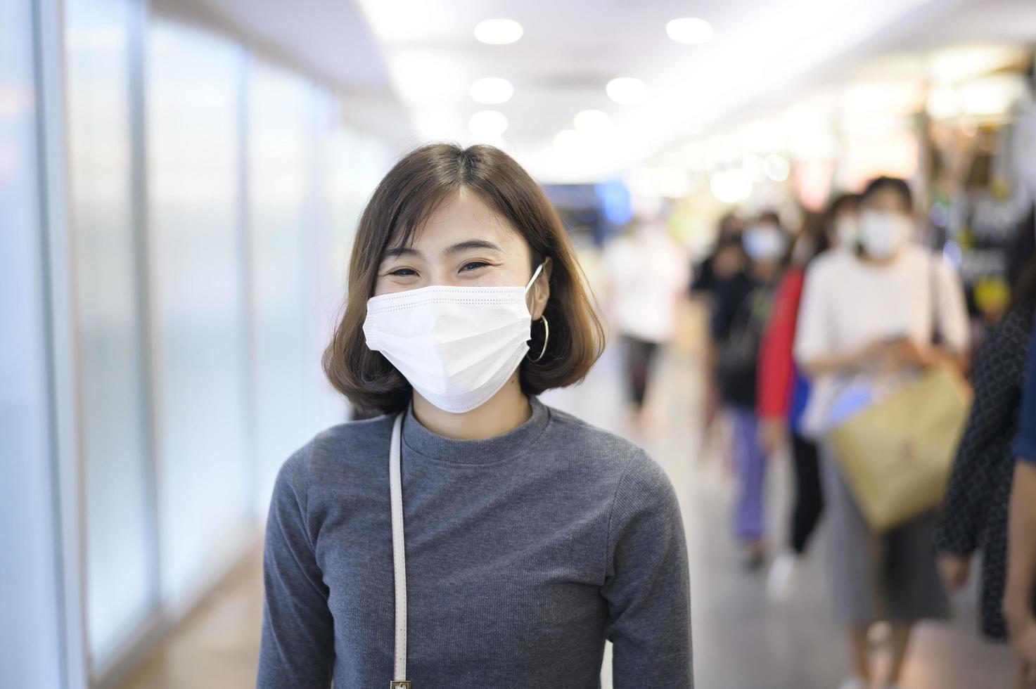 mulher usando máscara protetora fazendo compras sob pandemia covid-19 em shopping center, protocolo de distanciamento social, novo conceito normal. foto