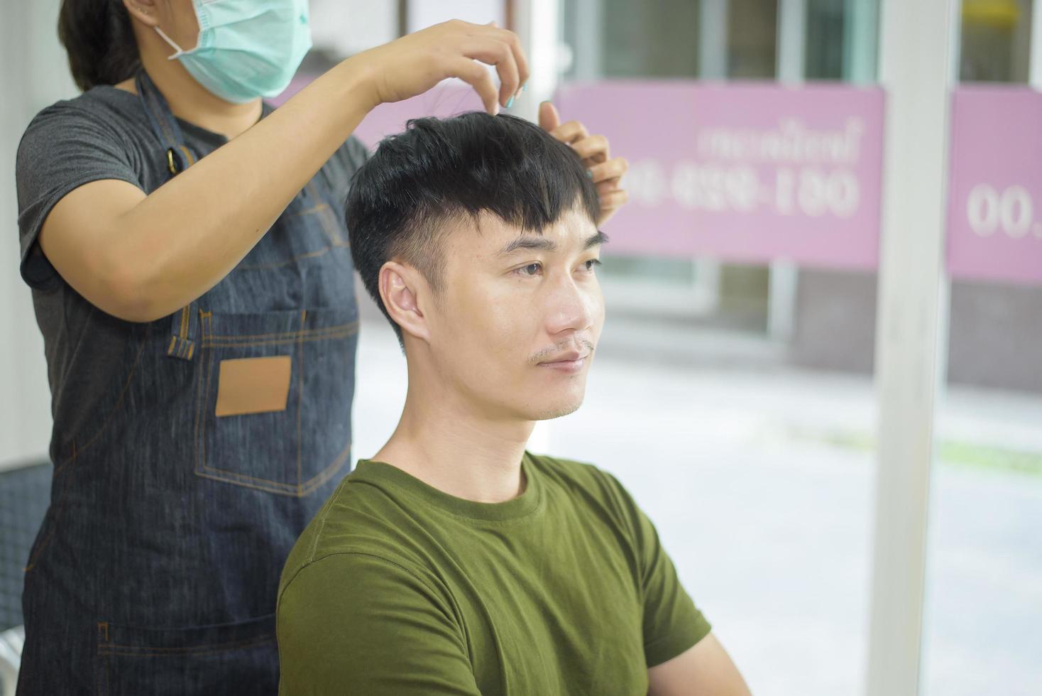um jovem está cortando o cabelo em um salão de cabeleireiro, conceito de segurança de salão foto