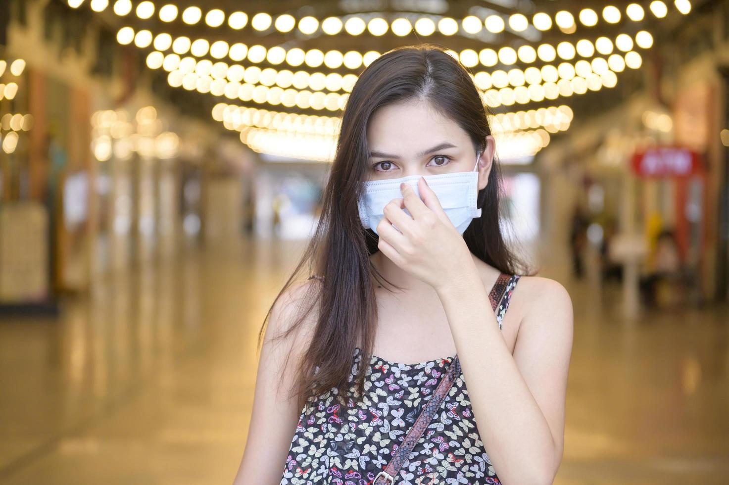 uma jovem asiática está usando máscara protetora fazendo compras no shopping center, proteção contra coronavírus, novo conceito de estilo de vida normal foto