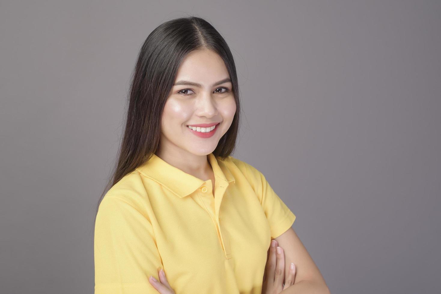 jovem mulher bonita confiante vestindo camisa amarela está no estúdio de fundo cinza foto