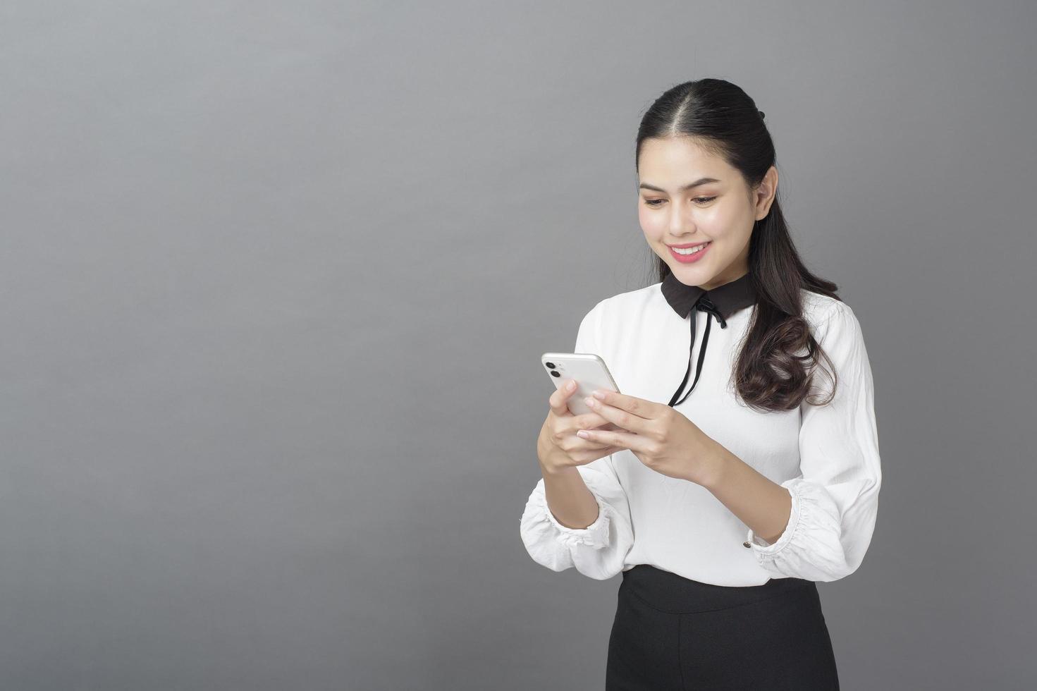 retrato de mulher de negócios linda está usando celular em estúdio foto