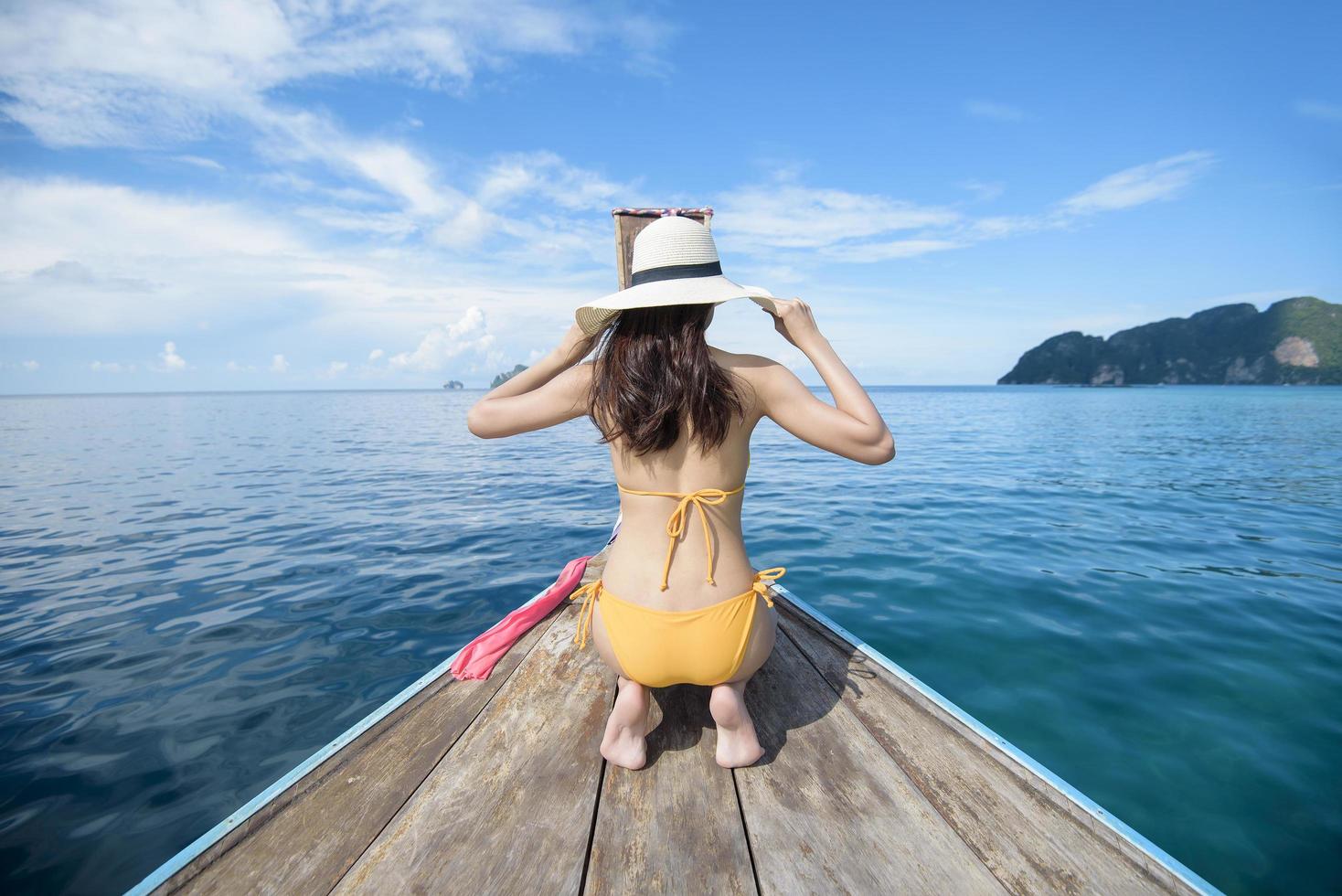 vista da mulher em traje de banho desfrutando no tradicional barco tailandês de cauda longa sobre a bela montanha e oceano, ilhas phi phi, tailândia foto