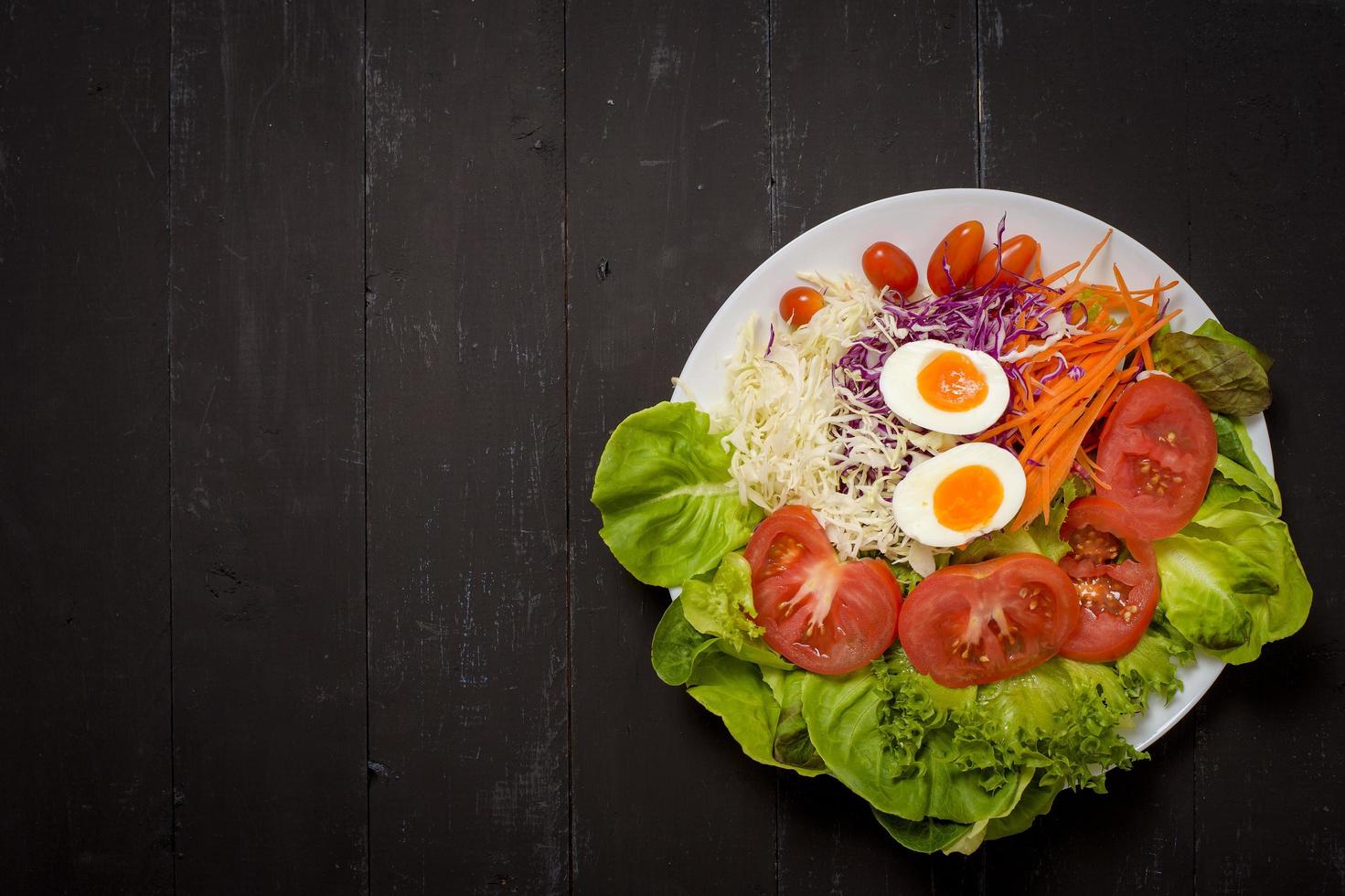 salada de legumes em fundo preto de madeira foto