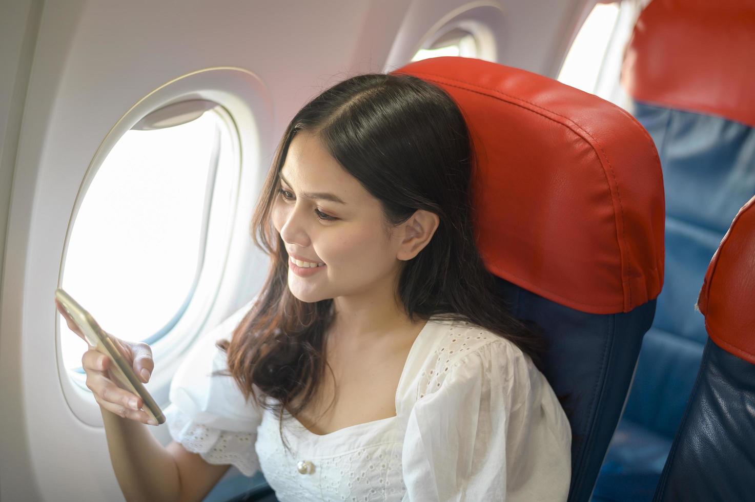 linda mulher viajante está usando smartphone no avião foto