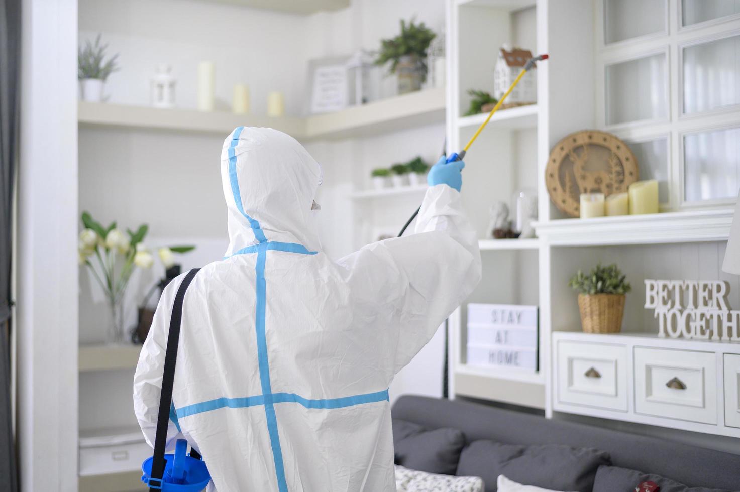 uma equipe médica em traje de EPI está usando spray desinfetante na sala de estar, proteção covid-19, conceito de desinfecção. foto