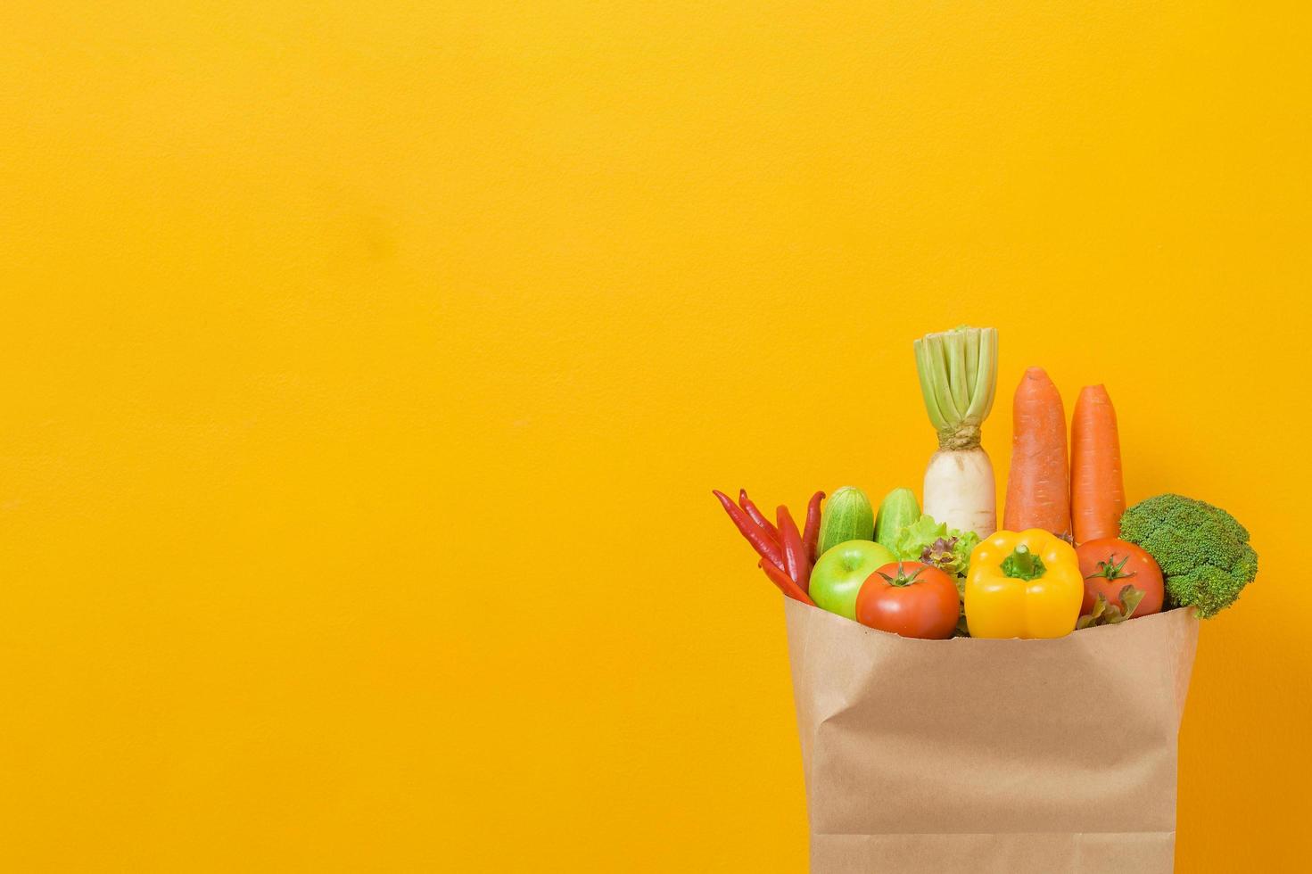 legumes na sacola de compras em fundo amarelo foto