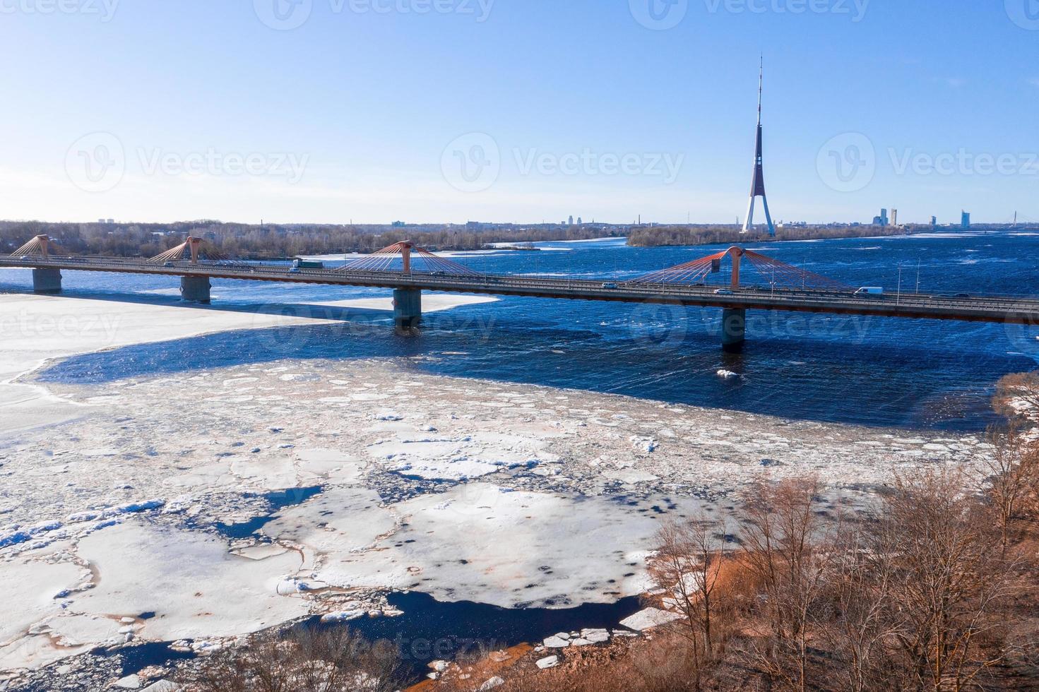 vista aérea da ponte sul sobre o rio daugava na letônia com padrões de gelo formados flutuando no rio. foto