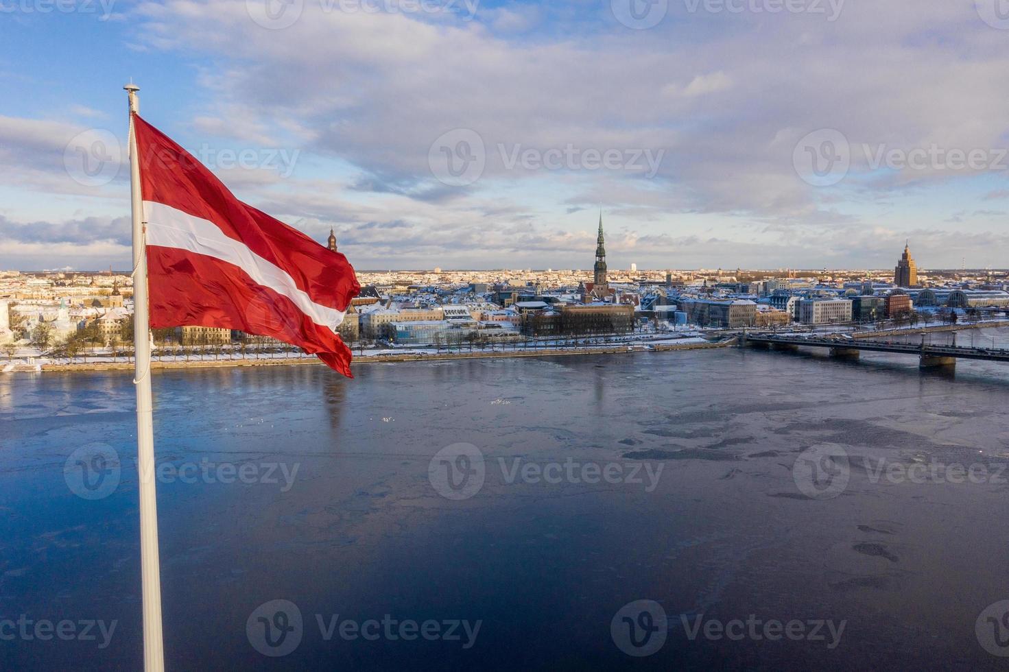 vista panorâmica da cidade de riga com uma grande bandeira letã pelo rio daugava. espírito letão. foto