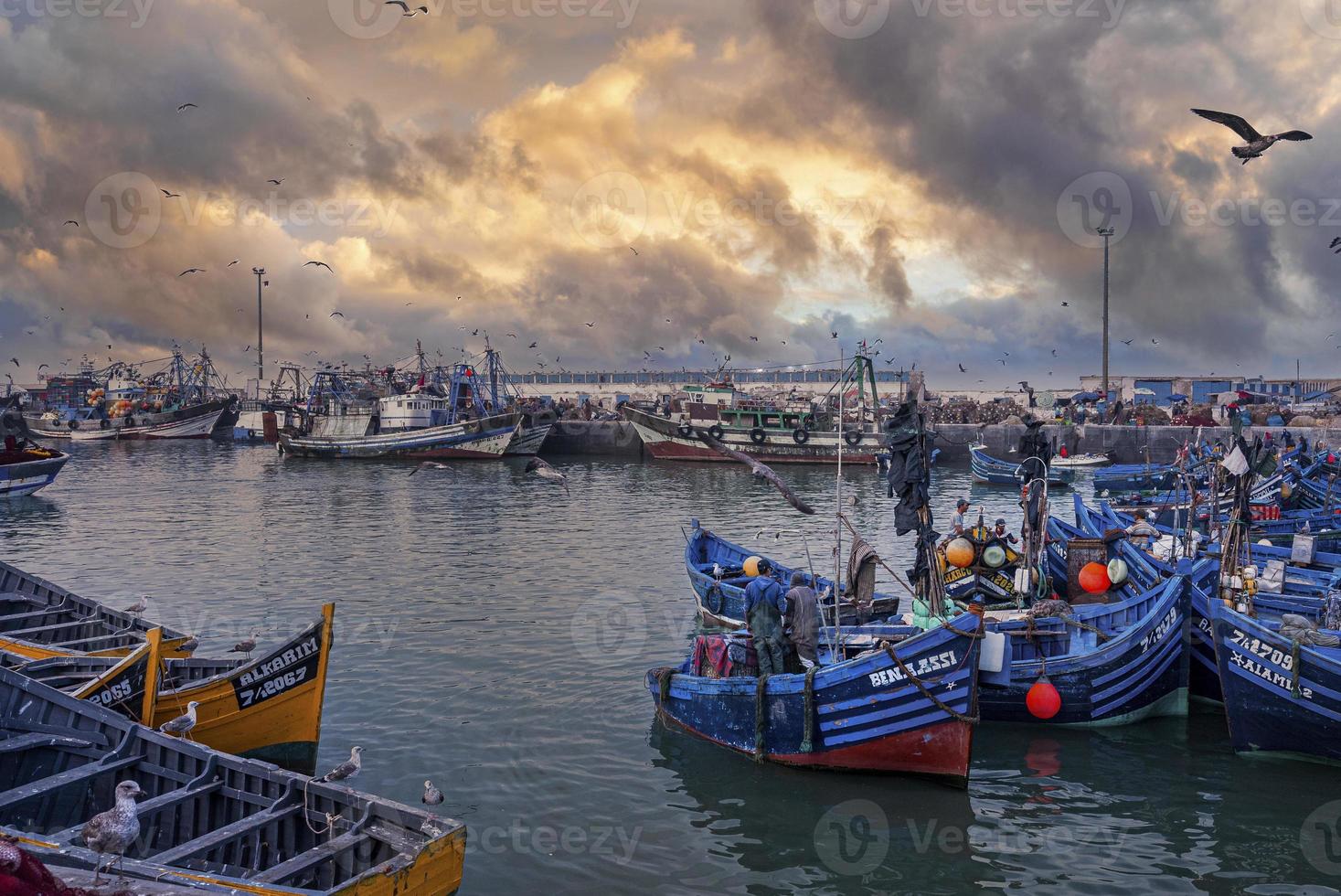 barcos de pesca de madeira ancorados na marina contra dramático céu nublado foto