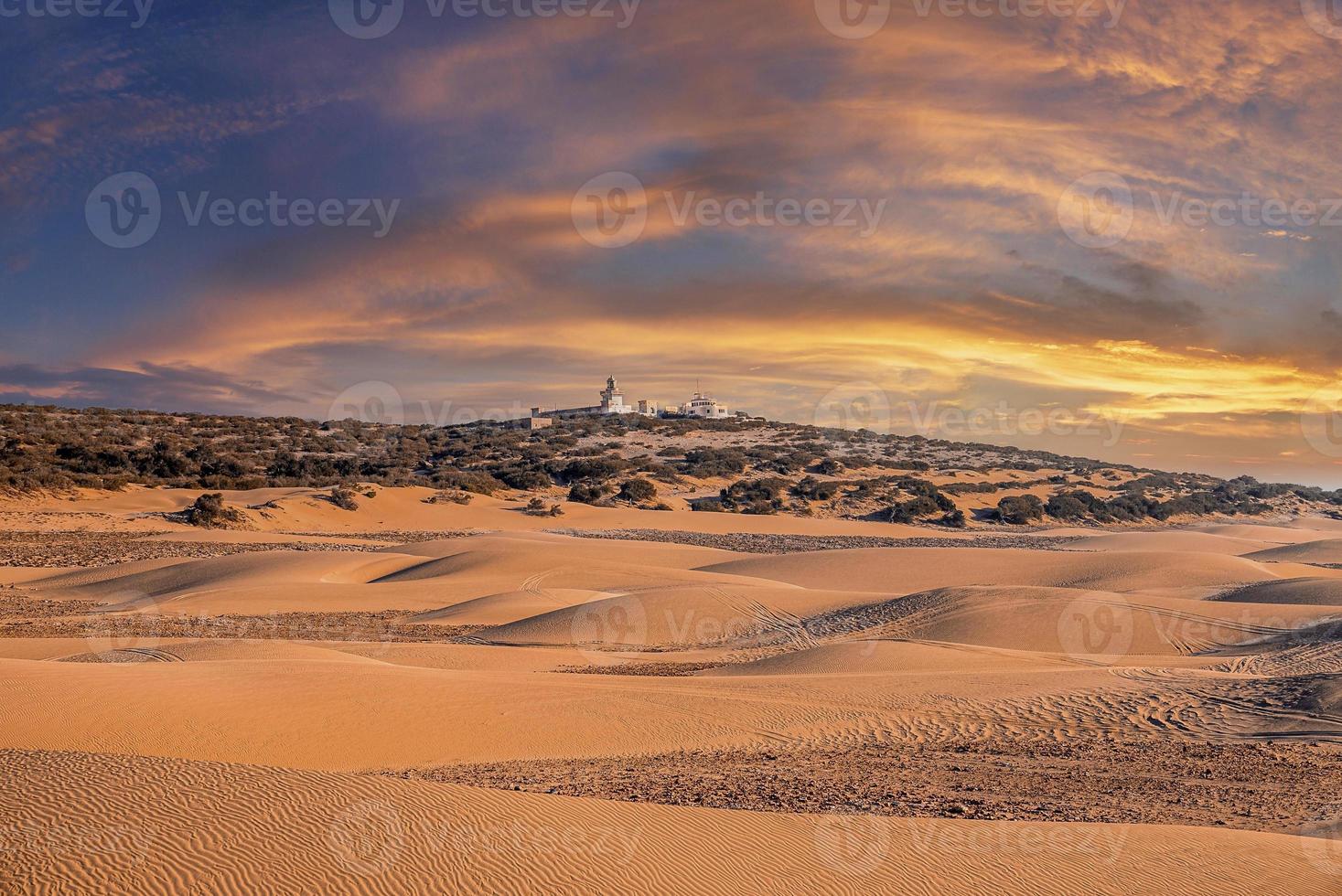 bela paisagem desértica de dunas de areia contra céu nublado ao pôr do sol foto