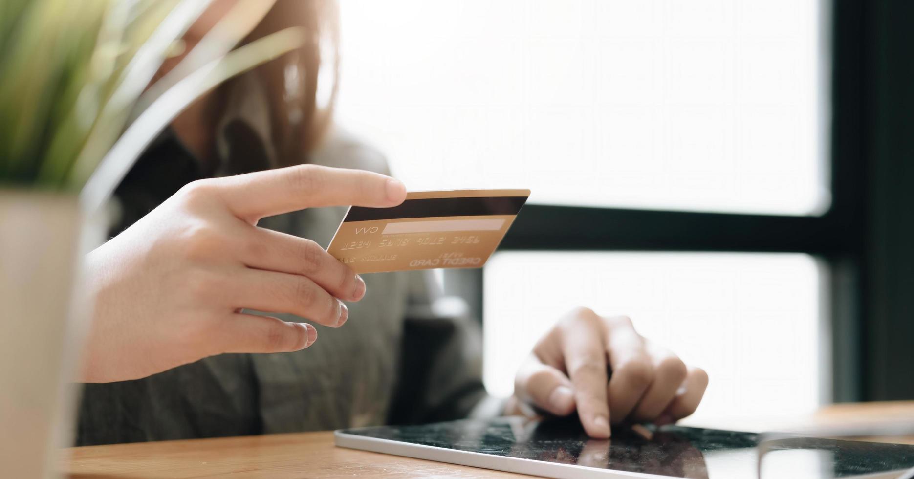 close-up garota faz uma compra na internet no tablet digital com cartão de crédito em casa foto