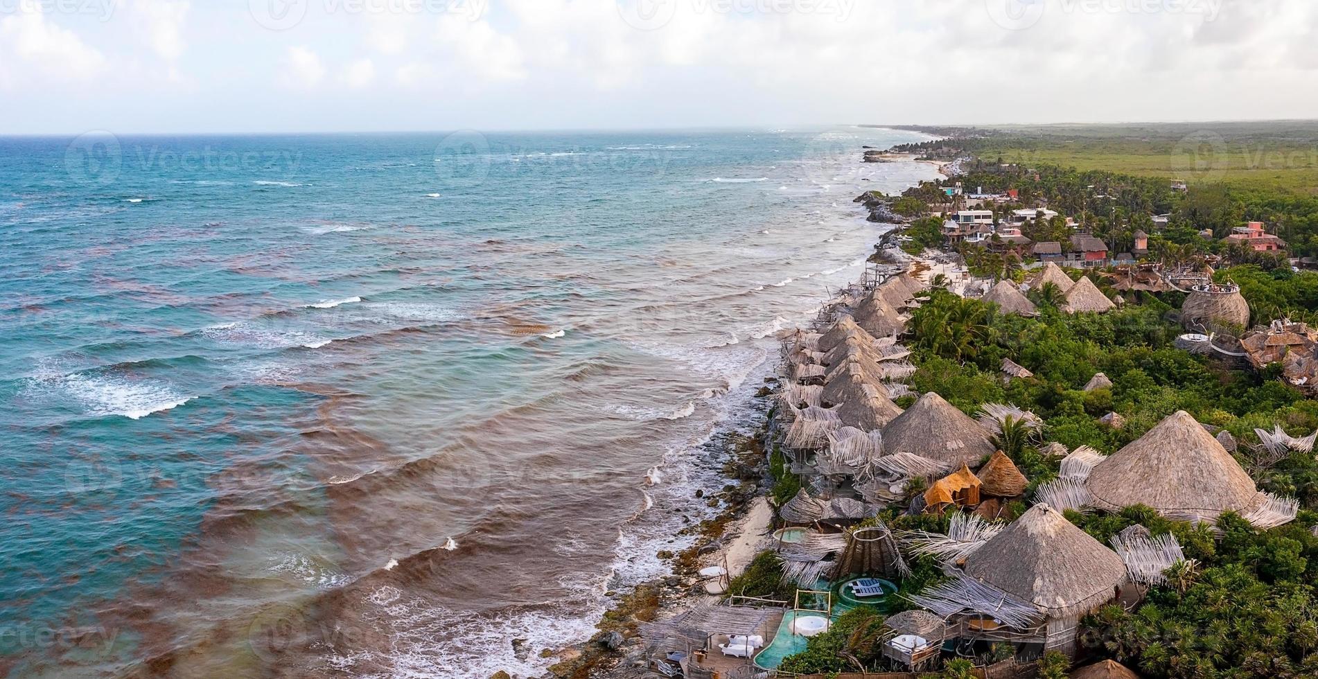 costa aérea de tulum na praia com um mar mágico do caribe e pequenas cabanas na costa. foto