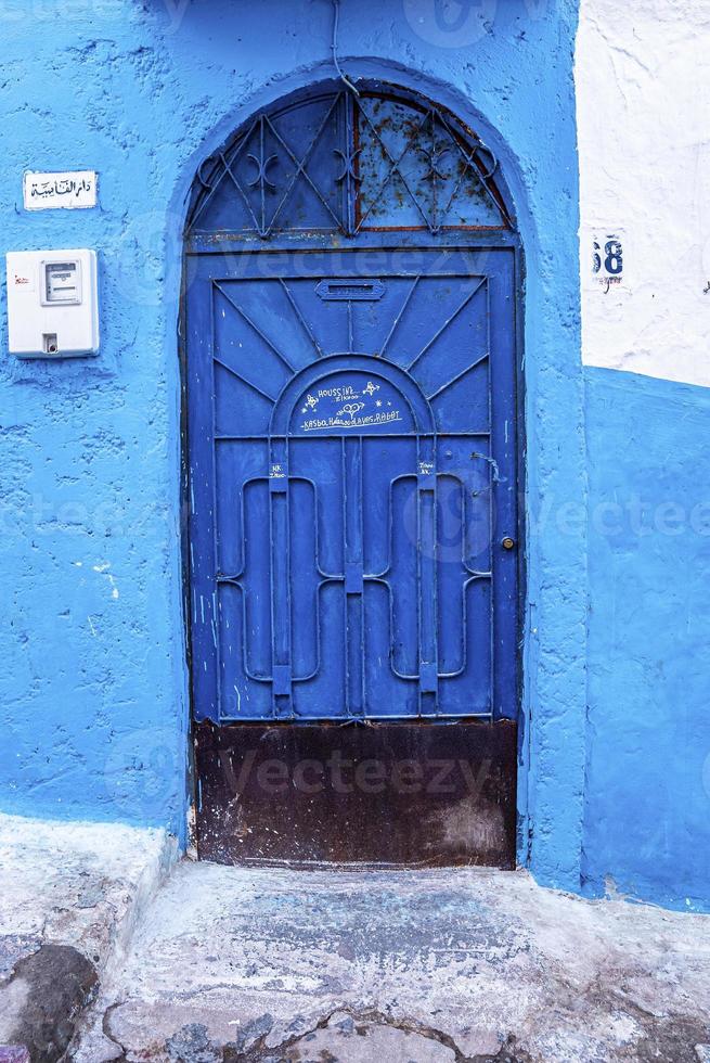 entrada em arco de uma casa tradicional com parede azul e porta fechada metálica foto