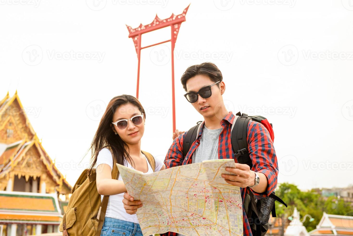 jovem casal de turistas asiáticos olhando para o mapa enquanto viajava em bangkok tailândia foto