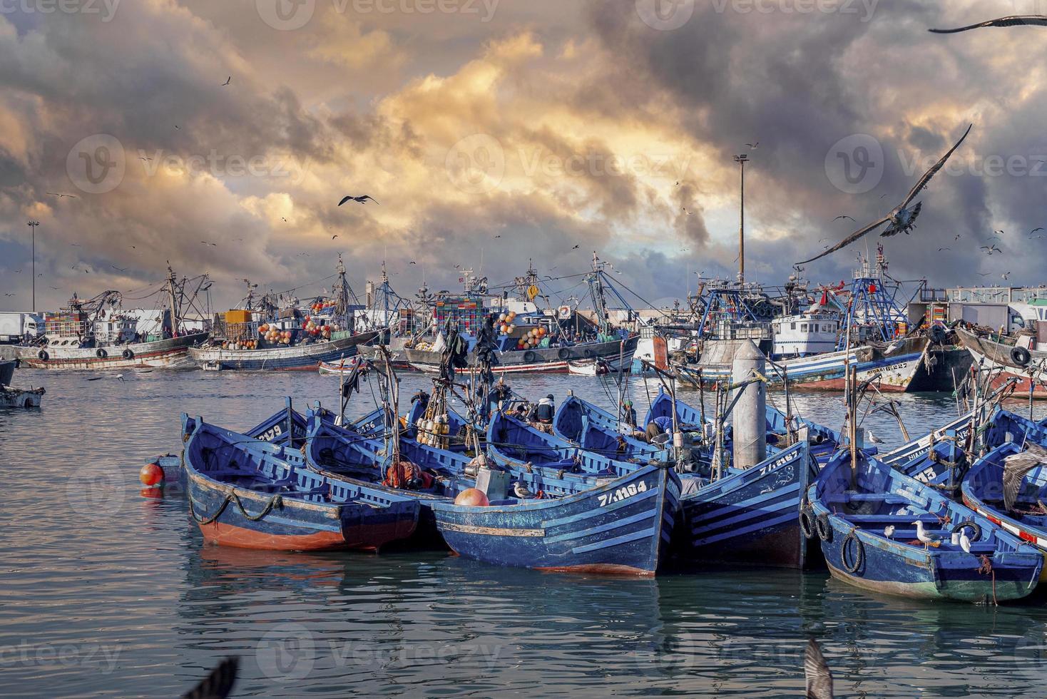 barcos de pesca de madeira ancorados na marina contra dramático céu nublado foto