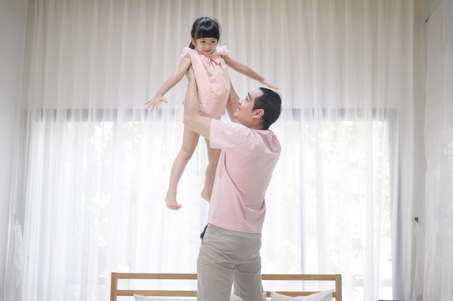 um pai saudável está segurando uma filha fofa feliz voando e jogando avião juntos em casa nos fins de semana, conceito de família. foto