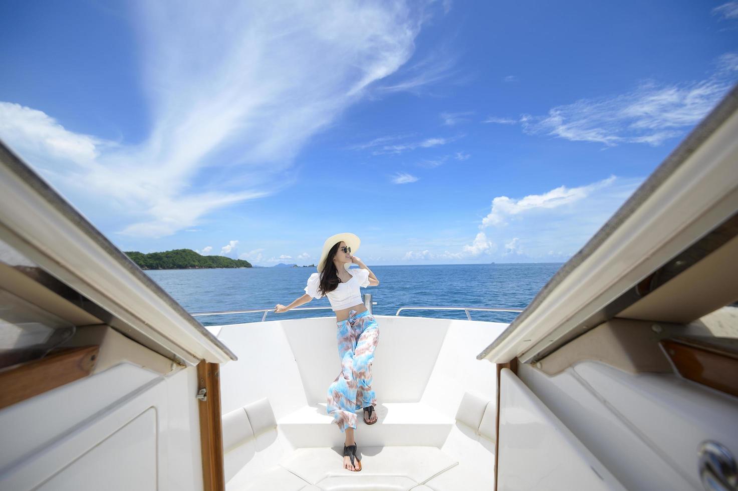 turista animado curtindo e relaxando na lancha com uma bela vista do oceano e da montanha no fundo foto