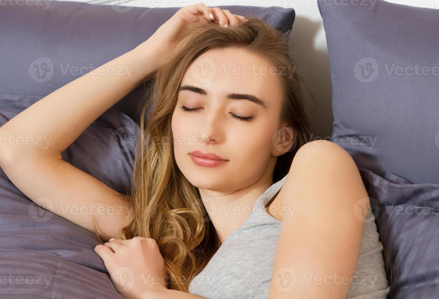 retrato de uma linda garota de sorriso com os olhos fechados na cama depois de dormir foto