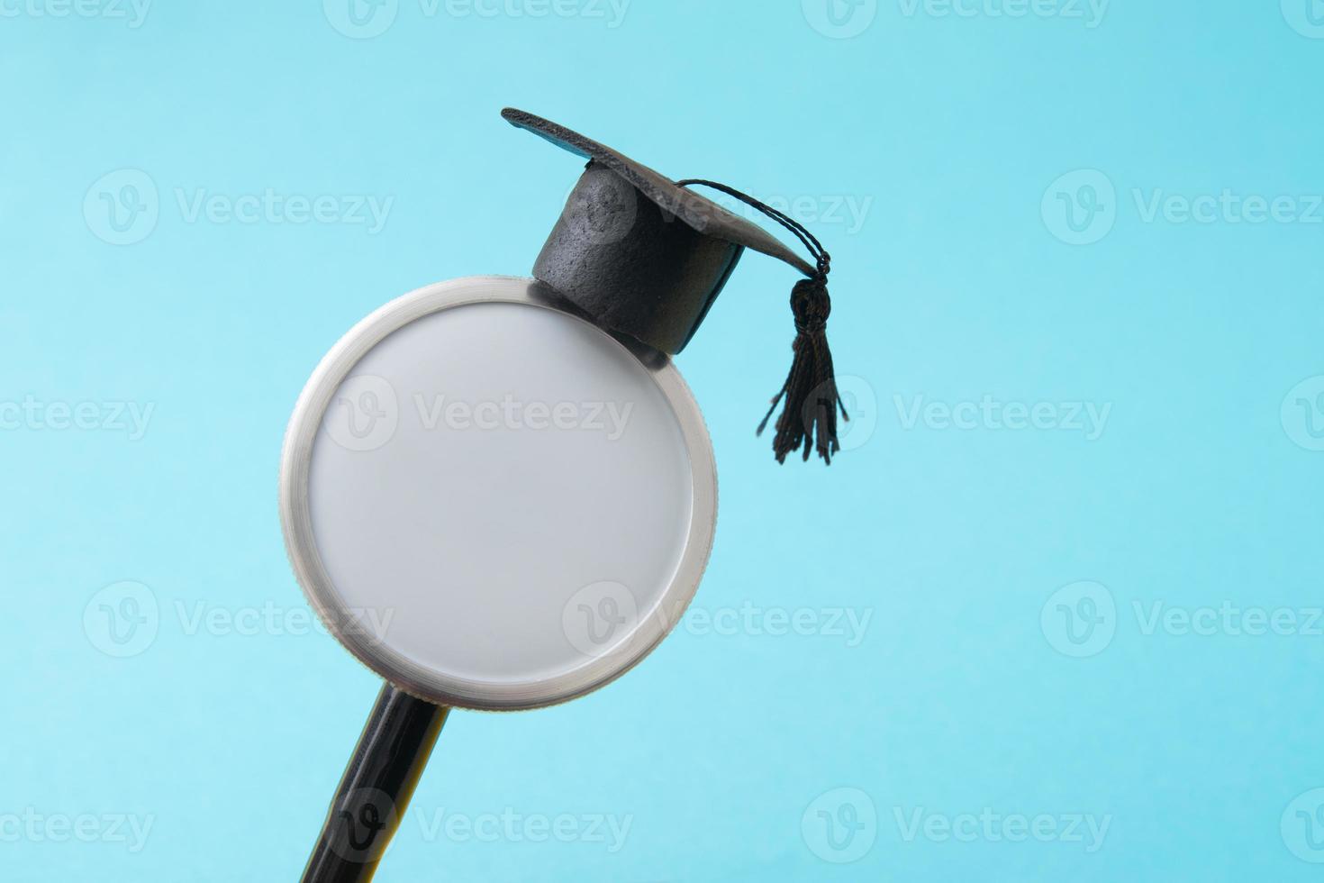 chapéu de formatura no estetoscópio médico simulado, fundo azul. escola de medicina, educação em saúde ou conceito de diploma universitário de médico foto