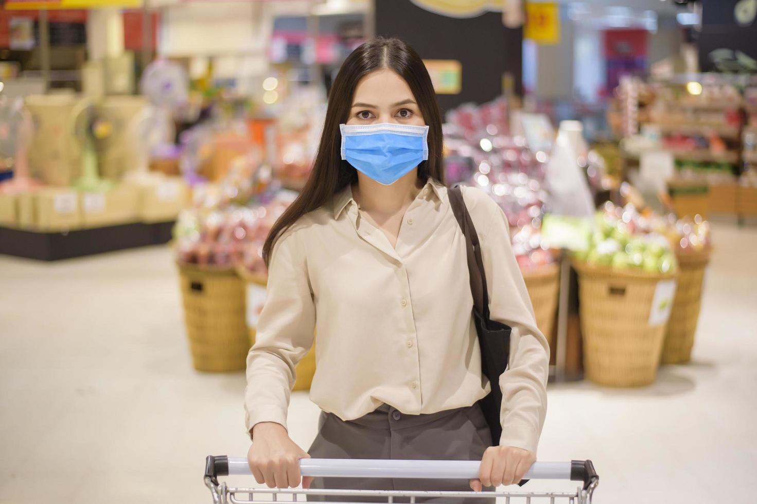 mulher está fazendo compras no supermercado com máscara facial foto
