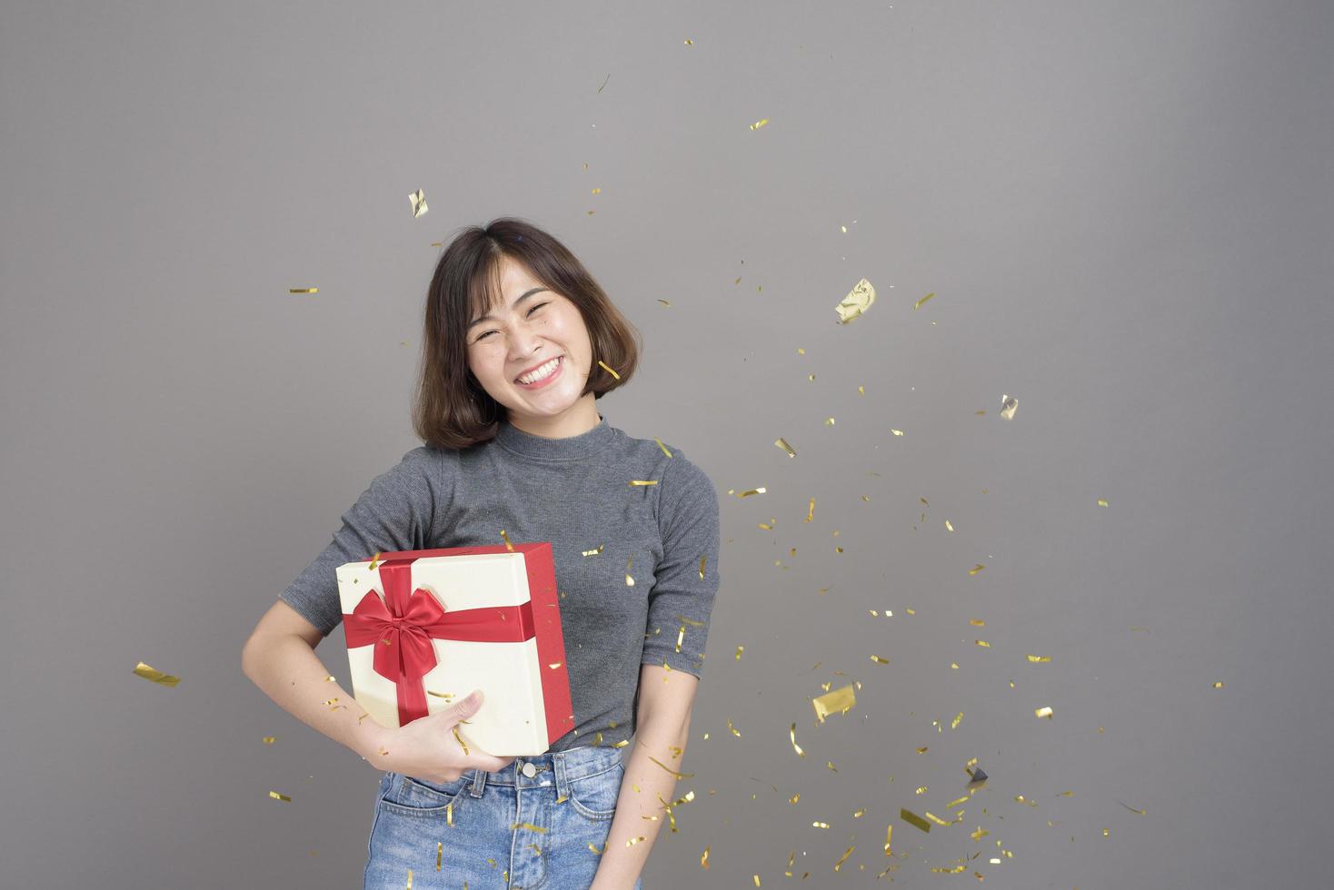 retrato de jovem e bela mulher asiática comemorando e jogando papel atirar isolado estúdio de fundo cinza, natal e conceito de ano novo. foto