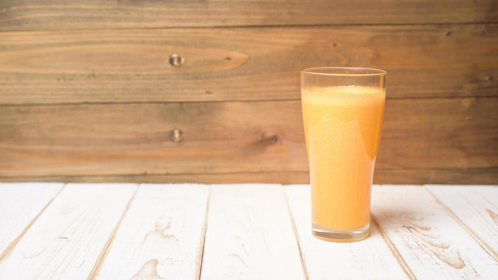 um copo de suco de laranja em fundo de madeira foto