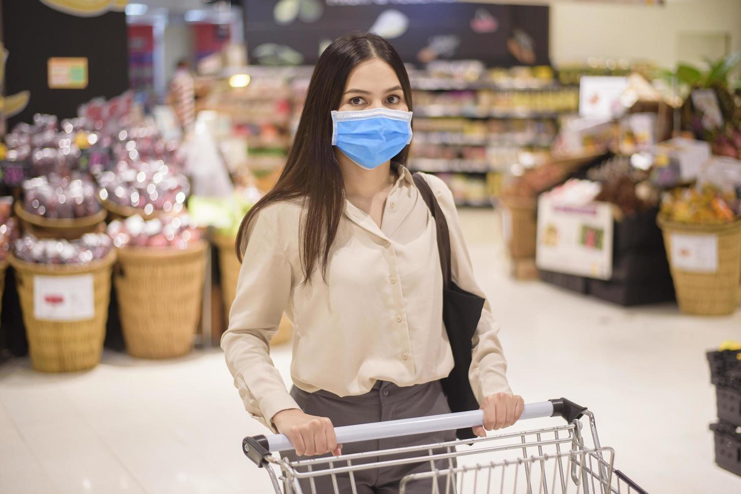 mulher está fazendo compras no supermercado com máscara facial foto