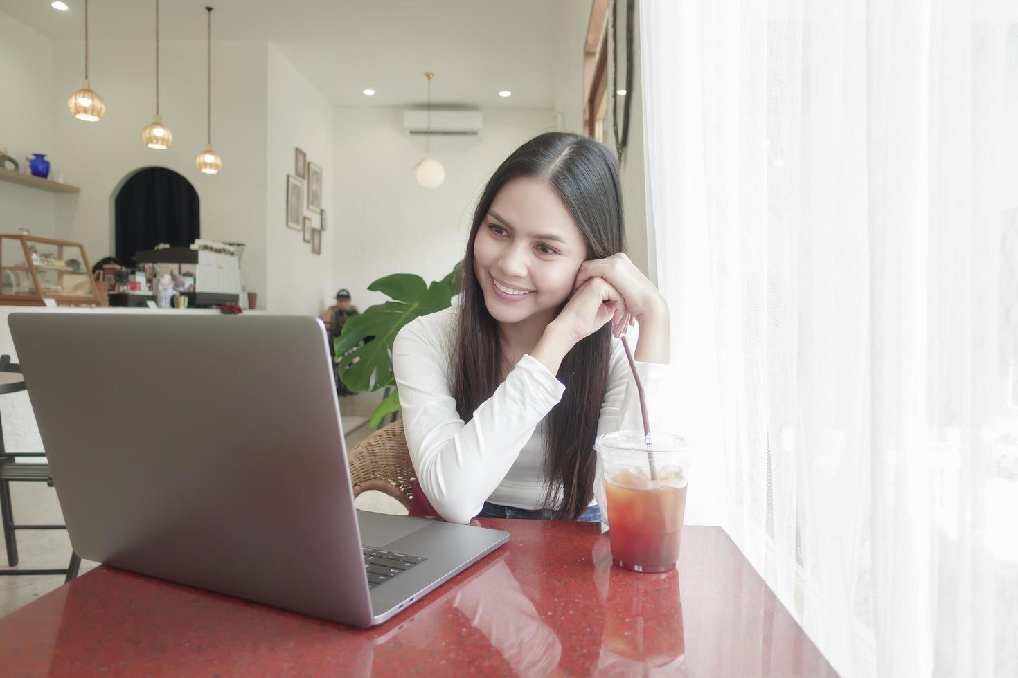 uma jovem está trabalhando com seu laptop no café foto