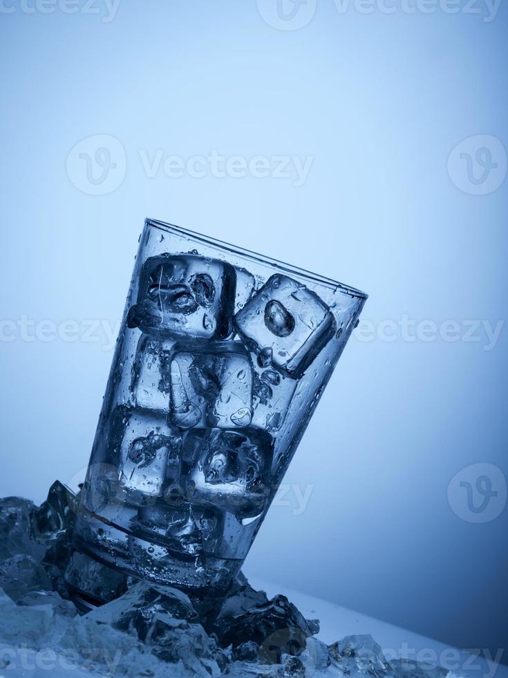 copo de água com cubos de gelo em um fundo azul claro foto