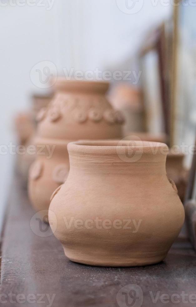 linha de potes de barro na prateleira, fundo desfocado. artesanato infantil foto