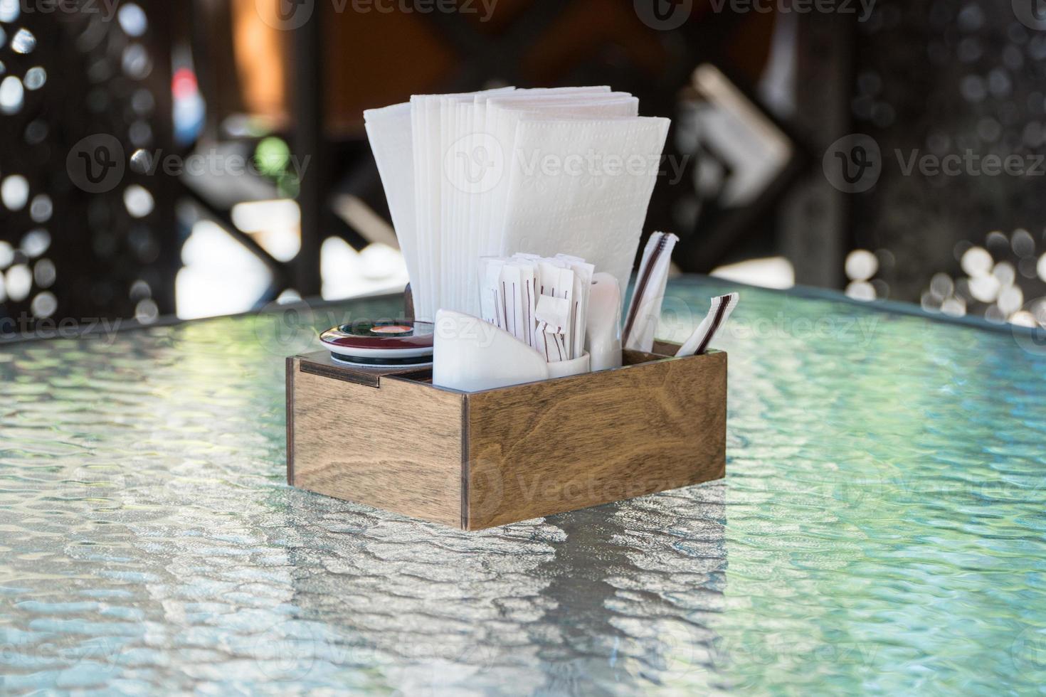 a caixa com guardanapos de papel em uma mesa de vidro, close-up. parte da mesa posta no café de verão ao ar livre foto