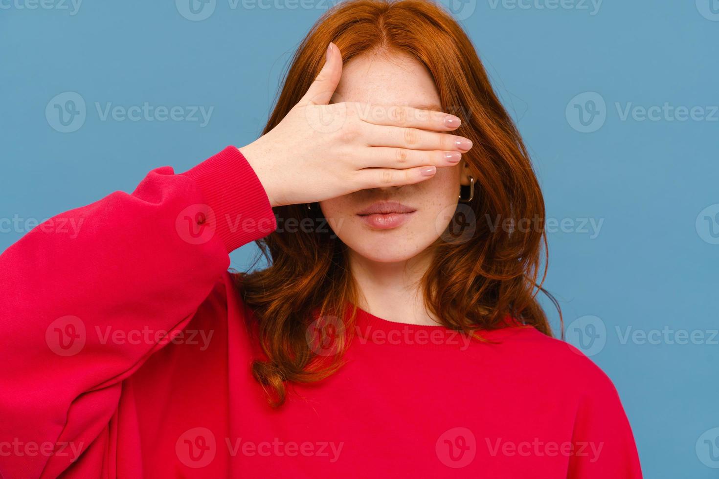 jovem ruiva vestindo suéter vermelho cobrindo os olhos foto