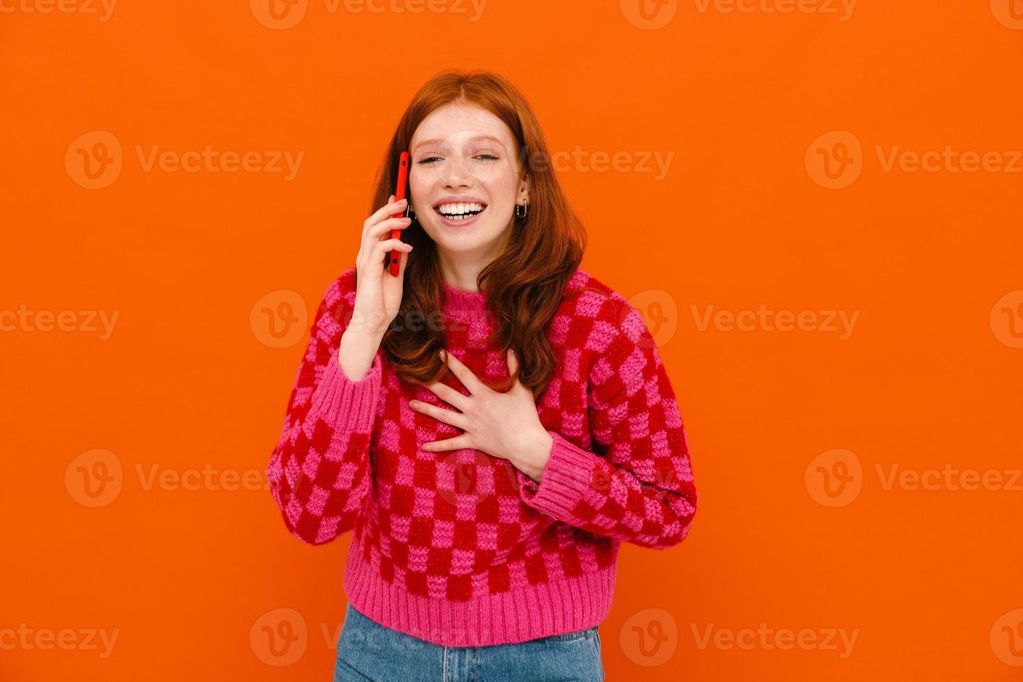 mulher ruiva de suéter xadrez rindo e falando no celular foto