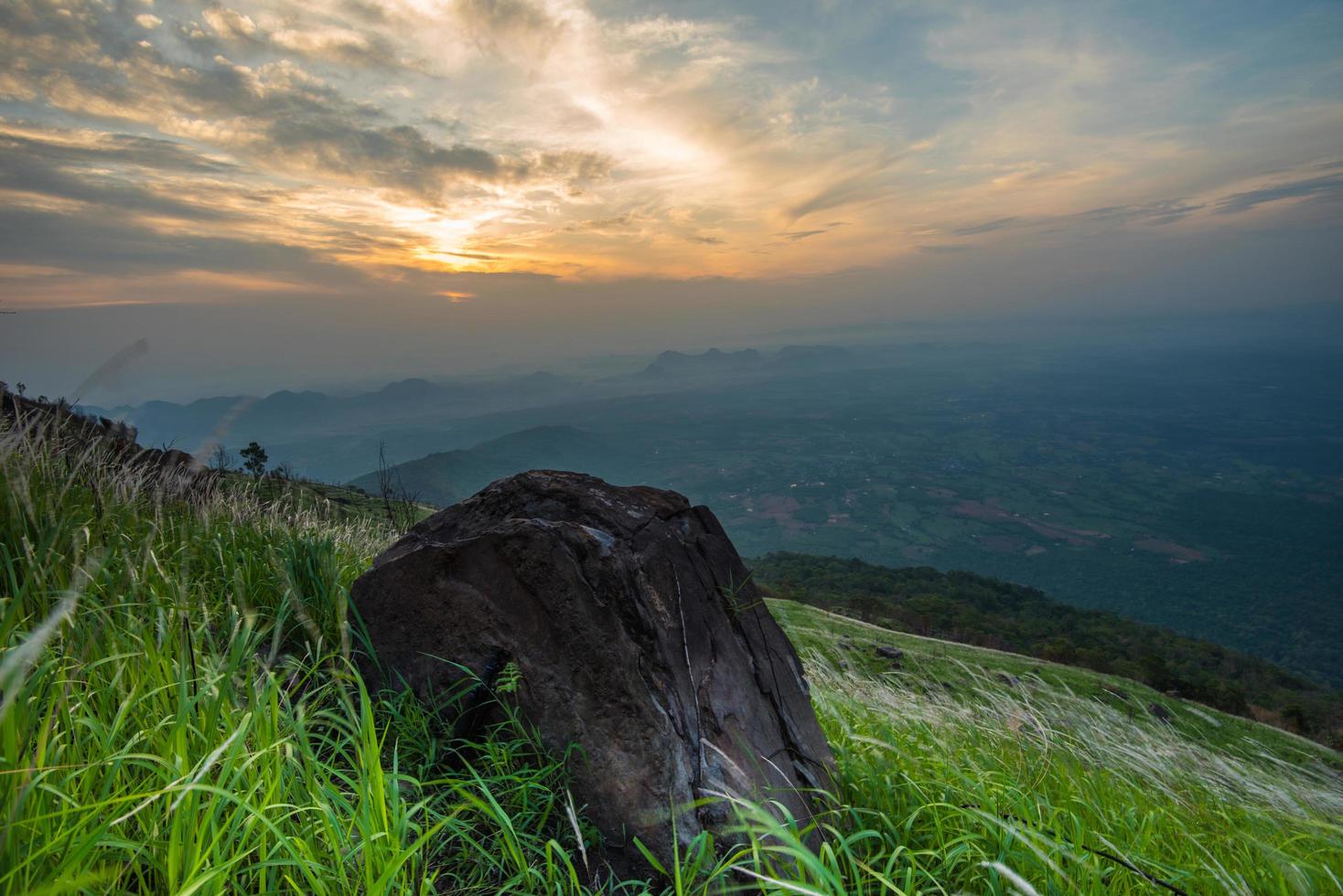paisagem nascer do sol na montanha da colina com pedra de pedra no prado de campo verde e céu colorido foto