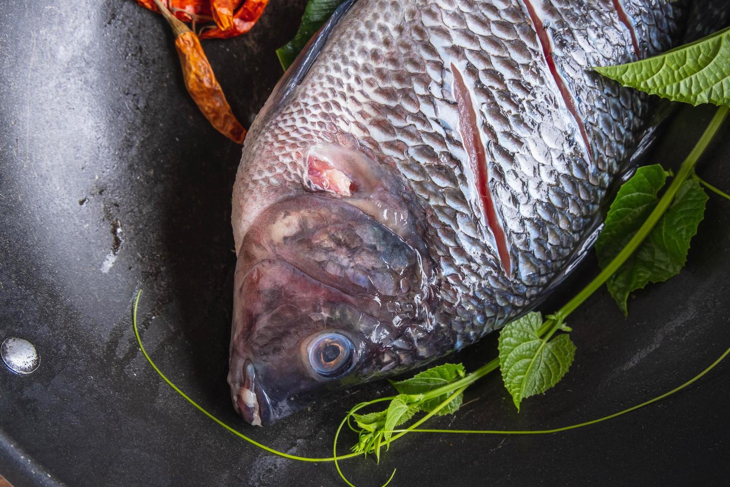 peixe fresco em uma panela e especiarias para cozinhar foto