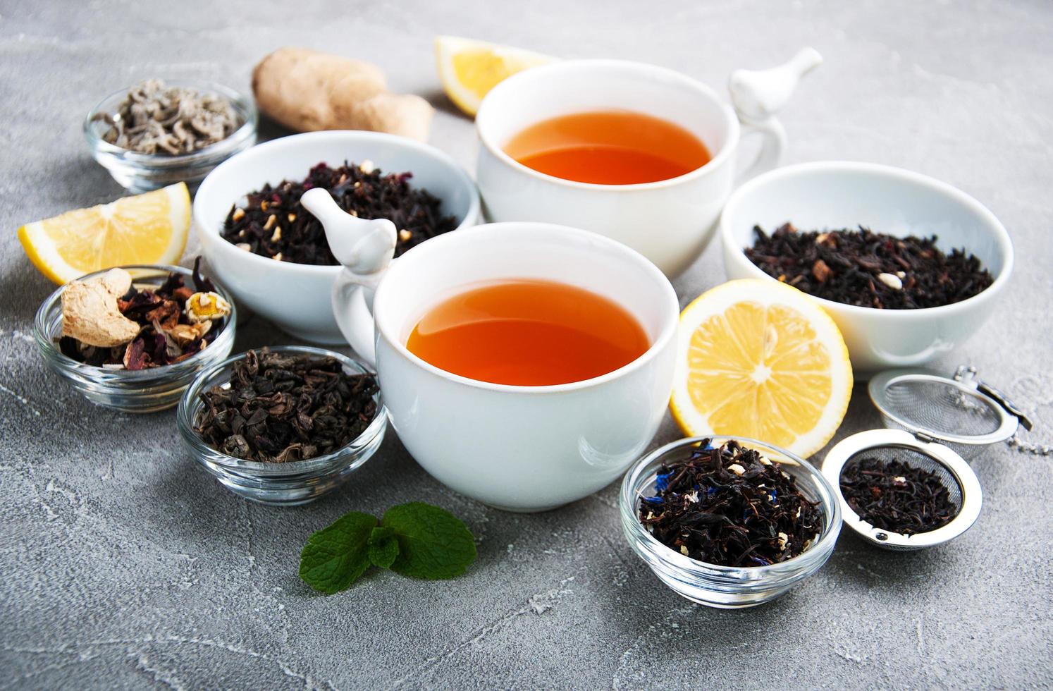 xícaras de chá com chá seco aromático em tigelas foto