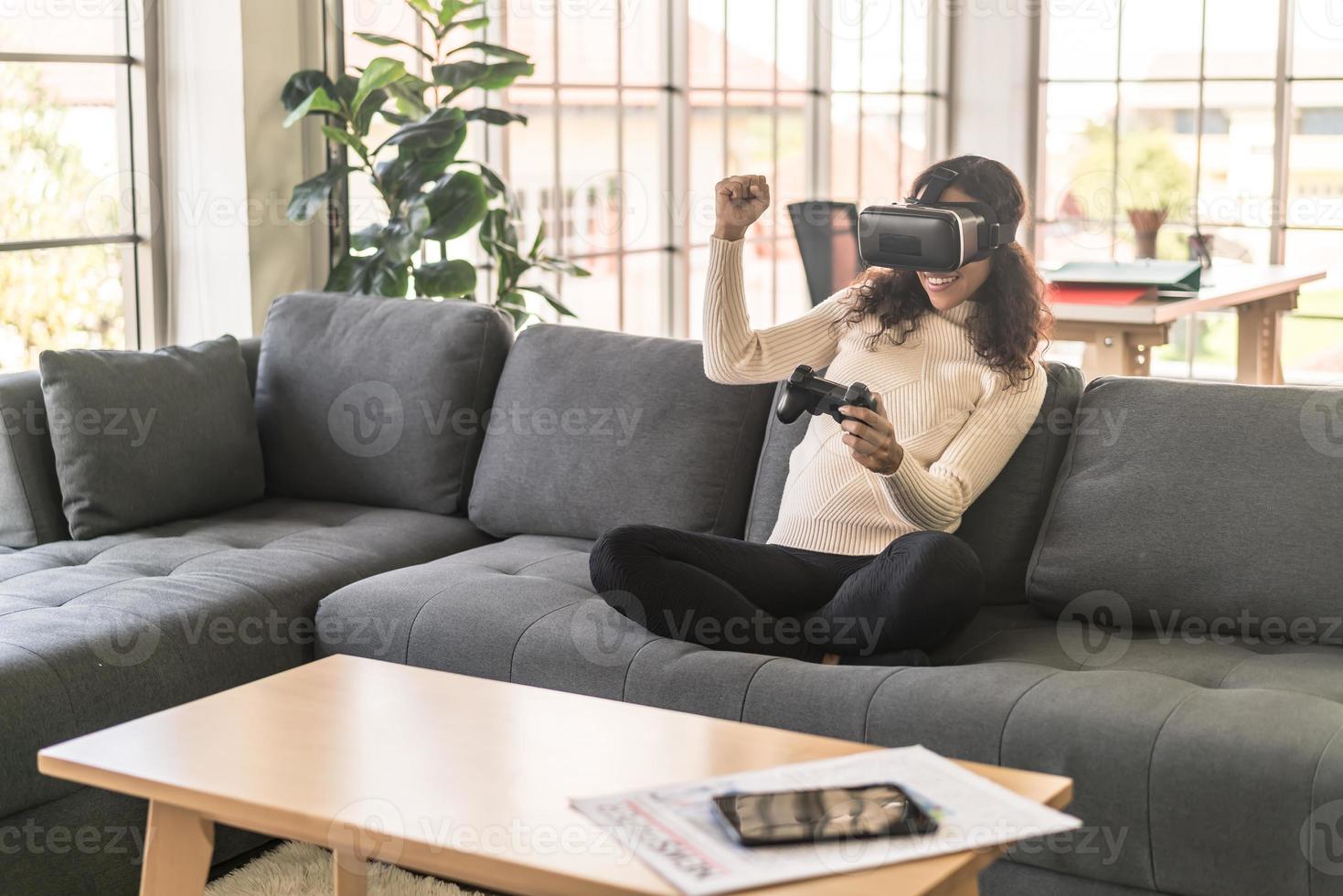 mulher latina usando um fone de ouvido de realidade virtual no sofá foto