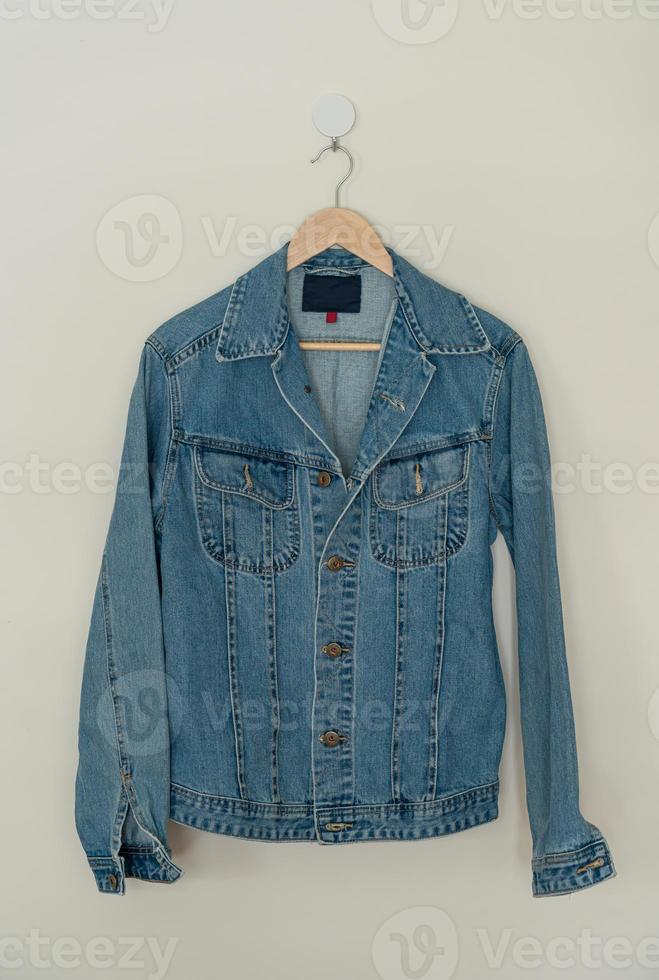 jaqueta jeans pendurada com cabide de madeira foto