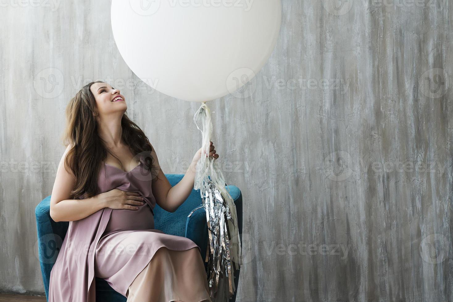 uma jovem grávida em um vestido roxo, sentado em uma cadeira. foto