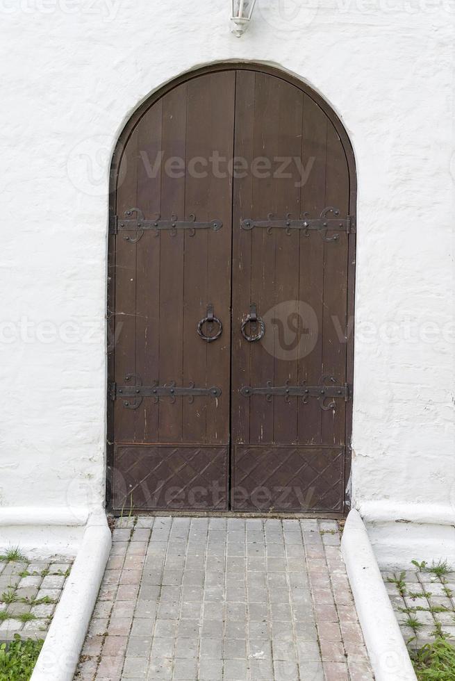 uma velha porta de madeira em arco com dobradiças de ferro. foto