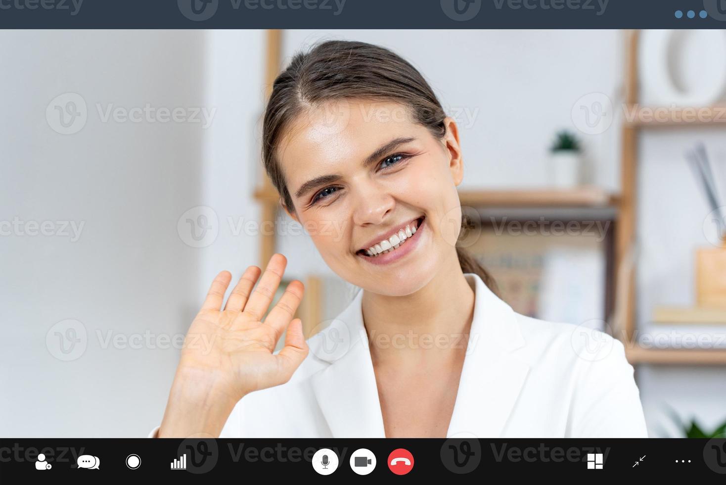 mulher caucasiana em traje de negócios formal, olhando para a câmera e acenando com a mão, tchau, enquanto faz videoconferência para trabalhar em casa conceito foto