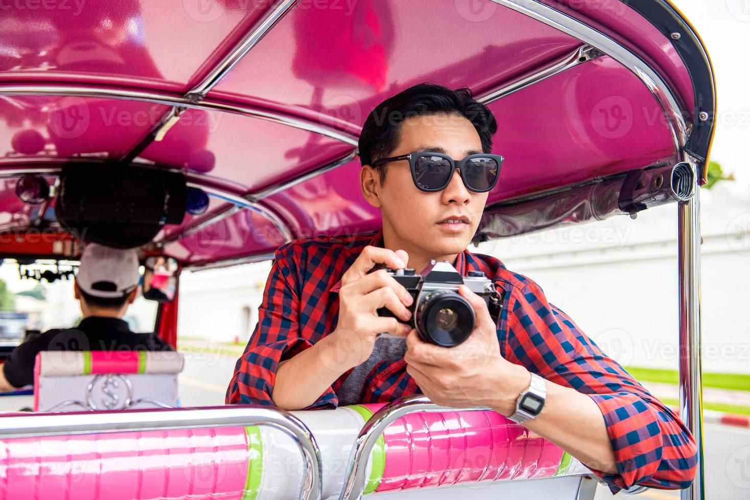 turista asiático masculino bonito segurando a câmera no táxi de tuk tuk em bangkok tailândia durante as férias de verão viajando sozinho foto